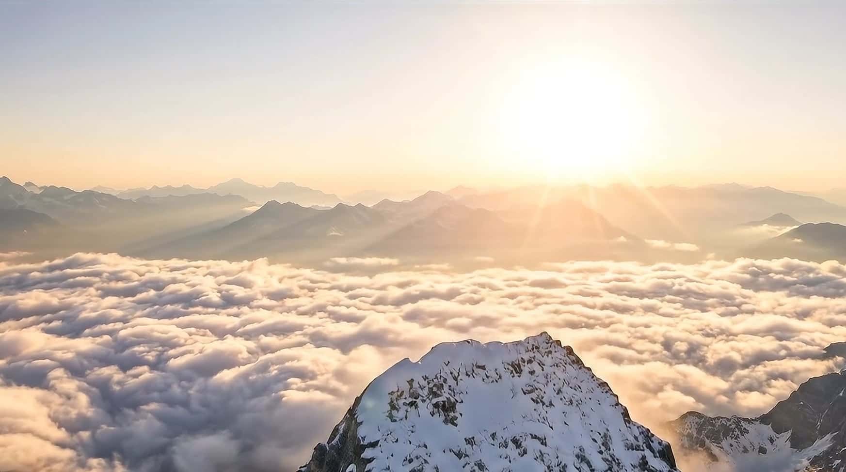 Above the summit at sunrise: the sun breaking over an endless sea of cloud and distant peaks
