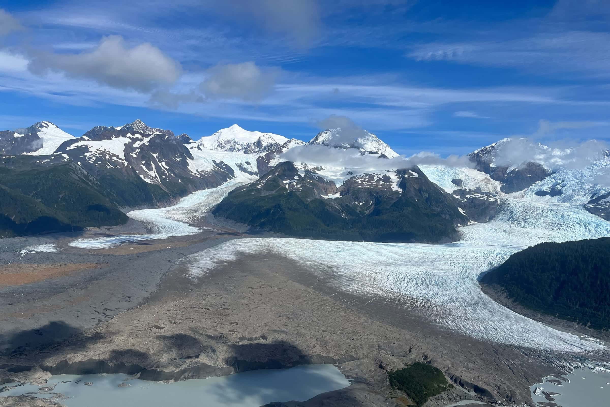 An aerial view of a branching glacier system with ice tongues, moraines and meltwater lakes